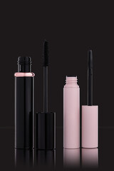 Opened black mascata and eyelash and eyebrow  care gel,  on black background