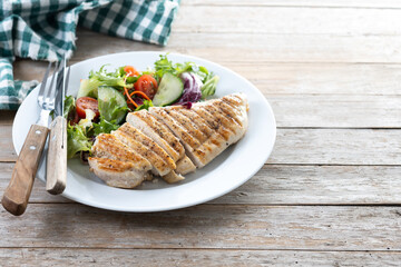 Healthy grilled chicken with salad on wooden table. Copy space