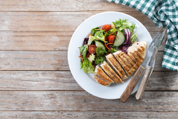 Healthy grilled chicken with salad on wooden table. Top view. Copy space