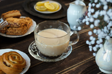 English breakfast. Cup of tea with milk and pastries on kitchen table.
