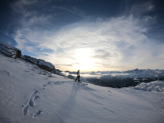 A stunning sunset view of a lone skier on a snowy slope, surrounded by untouched snow and dramatic skies.