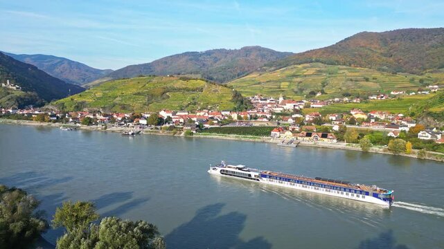 Aerial view of picturesque vineyards and a tranquil river with a cruise ship in autumn, Spitz, Austria.
