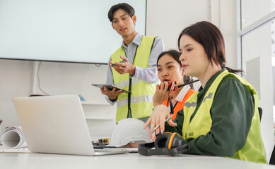 Construction team in a modern office discussing project updates with safety gear and technology in use