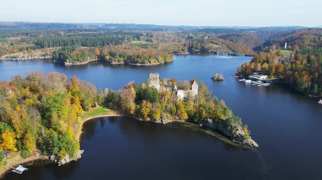 Aerial view of serene Stausee Ottenstein with a picturesque castle ruin surrounded by autumn forest, Zwettl, Austria.