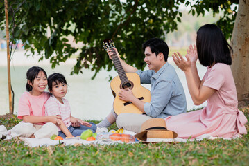 Young Asian family having a picnic in the park on the weekend
