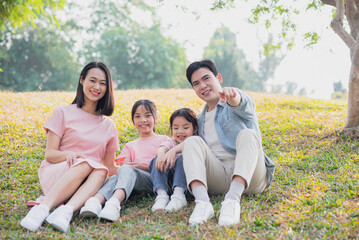 Young Asian family having a picnic in the park on the weekend
