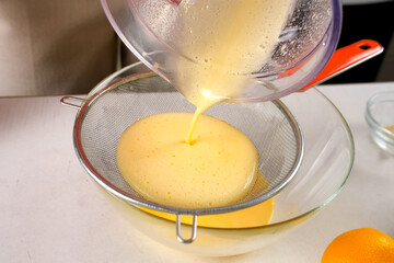 Pastry chef cooking tangerine pie filtering orange cream filling through sieve. Professional baker preparing ingredients for homemade pie. Culinary skills, cuisine, dish meal. Domestic recipe.