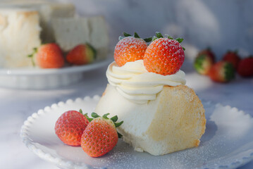angel food cake light and fluffy sponge cake served with whipped cream and strawberry on white plate.