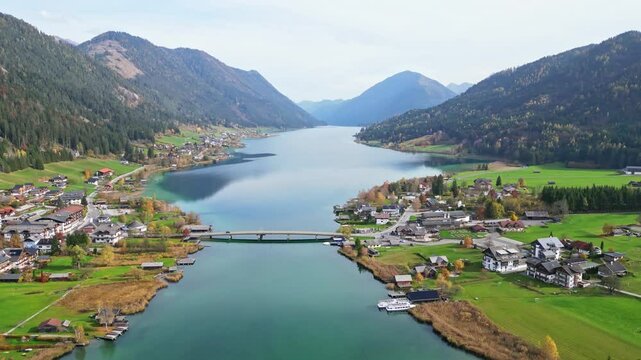 Aerial view of idyllic autumn landscape with serene Weissensee lake, picturesque village, and tranquil mountains, Carinthia, Austria.