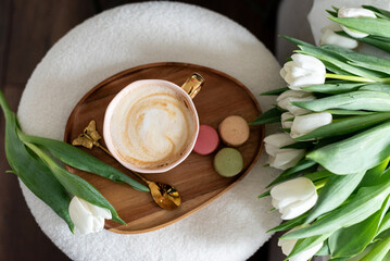 Cup with cappuccino and macarons, spring flowers tulips, morning concept, soy candle, woman's day, bedroom design