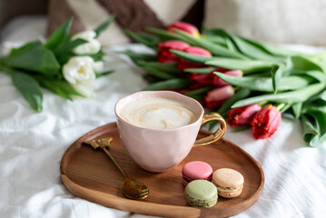 Cup with cappuccino and macarons, spring flowers tulips, morning concept, soy candle, woman's day, bedroom design