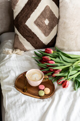 Cup with cappuccino and macarons, spring flowers tulips, morning concept, soy candle, woman's day, bedroom design