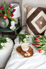 Cup with cappuccino and macarons, spring flowers tulips, morning concept, soy candle, woman's day, bedroom design