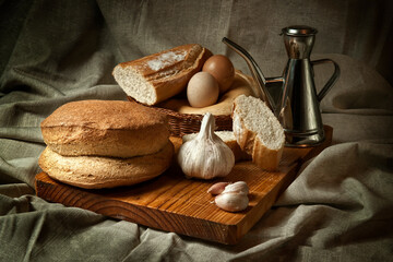 Still life with bread, garlic, eggs and oil on a sackcloth background. Food