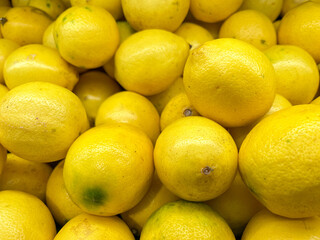 A vibrant pile of fresh, bright yellow lemons with smooth, slightly textured skin
