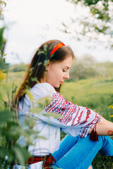 Woman in Traditional Embroidered Blouse Posing Outdoors Amid Greenery and Flowers