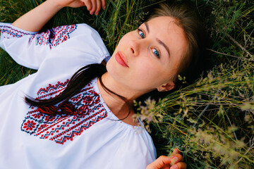 Smiling Woman in Embroidered Blouse Relaxing on Grass Outdoors