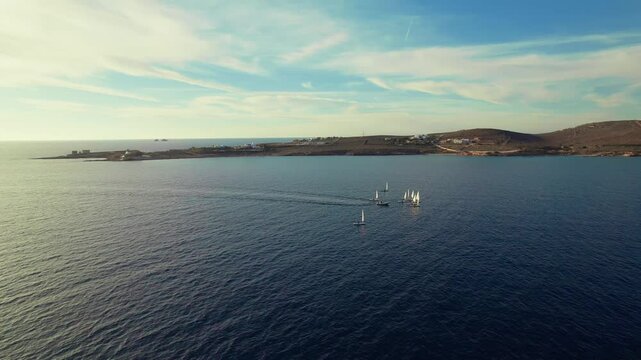 Drone shot of sail&iota;ng boats with sails outside of Parikia town on Paros island in Greece. Drone flying around them