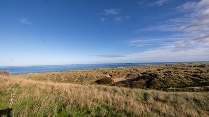 Sand dunes and grass on the Northumberland coast. Farne islands in the distance