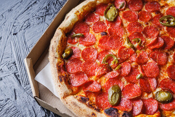 delicious pepperoni pizza with jalapeno peppers in a delivery box