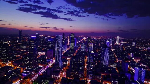 Time-Lapse Drone: A glowing city skyline transitioning from day to night, warm golden hues shifting to vibrant city lights, with a dynamic, travel or awe inspiring tone.
