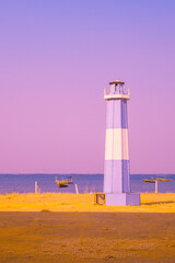 Infrared photography,  lighthouse painted in blue and white stripes, standing near the shore