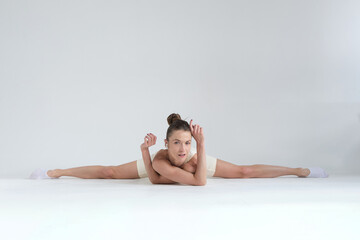A flexible woman performs a full split while resting on the floor, maintaining a calm and confident...