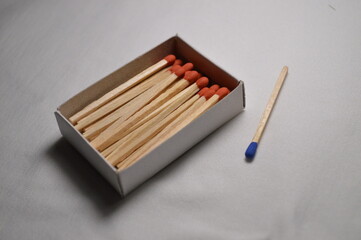 A box of matches sits on a table with one match laying next to it.