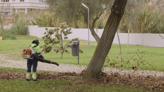 Gardener blowing leaves in a park