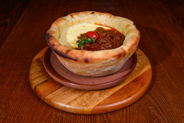 Goulash with mashed potatoes in pottery casserole