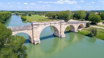 Fototapeta premium Historic Roman Bridge Over Serene River with Lush Green Surroundings