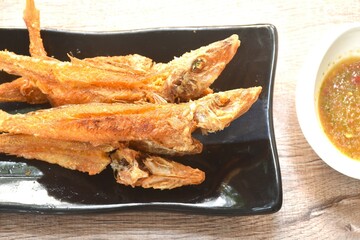 crispy fried sand whiting fish arranging on plate dipping spicy chili sauce in cup
