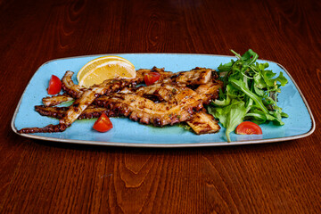 Grilled octopus with lemon on plate 