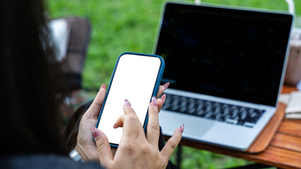 Close up of female hand using mobile phone and laptop in park on sunny day