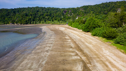 Aerial view of a wide sandy beach and dense tropical jungle at Bako, Borneo