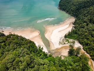 Aerial shot of a sandy beach surrounded by dense tropical rainforest at Bako, Borneo