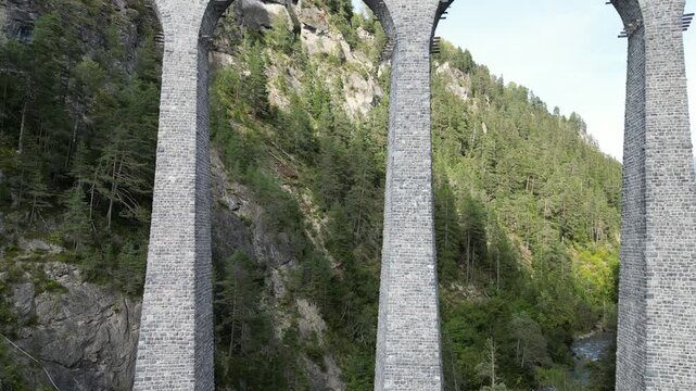 Aerial view of the landwasser viaduct crossing a scenic valley surrounded by mountains and forests, Zuoz, Switzerland.