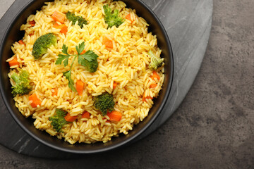 Tasty rice with vegetables served on grey table, top view