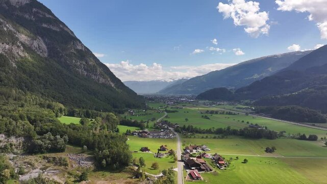 Aerial view of a picturesque valley surrounded by lush mountains and a serene village, Mels, Switzerland.