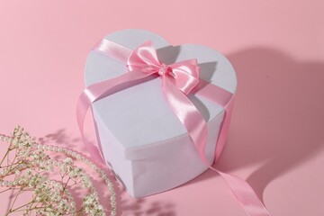 Beautiful wedding gift, pearl jewelry and gypsophila flowers on pink background, closeup