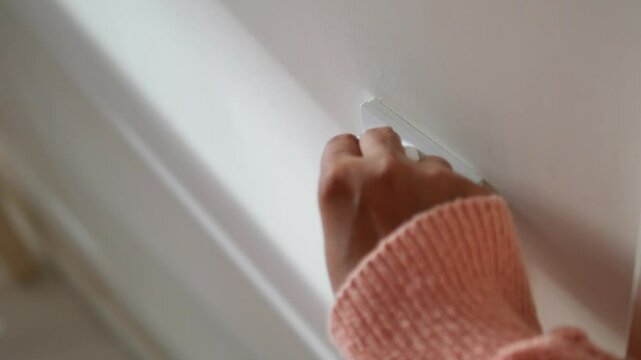 hand with cloth wiping a light switch at the wall