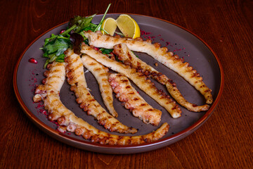 Grilled octopus with lemon on plate 
