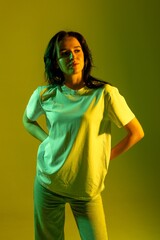 Model poses confidently against a vibrant yellow-green background in a casual outfit showcasing modern style and attitude