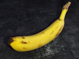 Yellow banana on a dark background. Fresh healthy fruit theme.