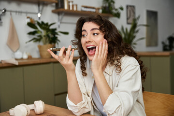 Joyful young woman enjoying a lively conversation at home in a cozy, stylish kitchen setting