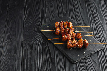 delicious juicy Japanese yakitori skewers on a black wooden rustic background