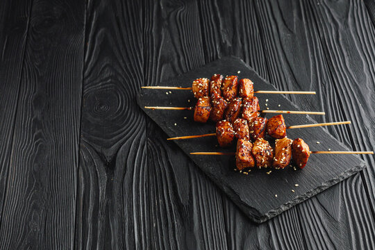 delicious juicy Japanese yakitori skewers on a black wooden rustic background