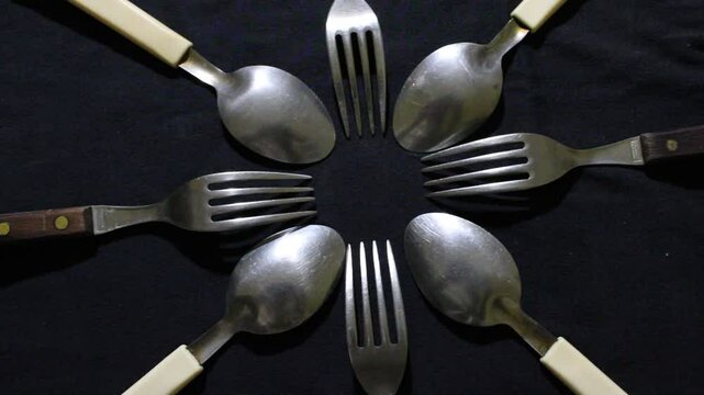 Cucharas grandes y peque&ntilde;as en c&iacute;rculo, son herramientas culinarias para comidas variadas, forman un dise&ntilde;o de brillos y texturas abstractos con fondo negro