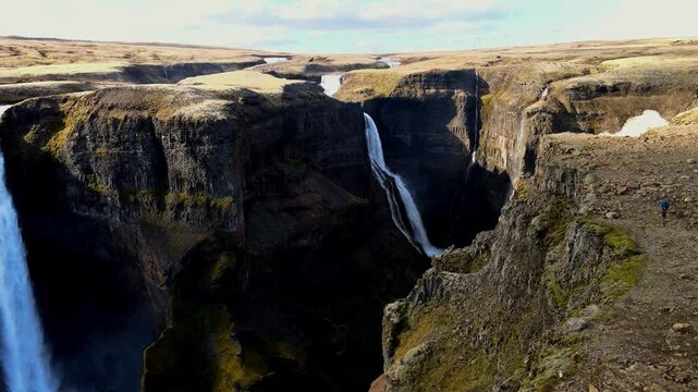 Aerial view of haifoss and granni waterfalls cascading down rugged cliffs in a serene canyon, Hella, Iceland.