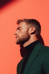 Obraz premium Businessman closing eyes, wearing green suit and black turtleneck, on orange background